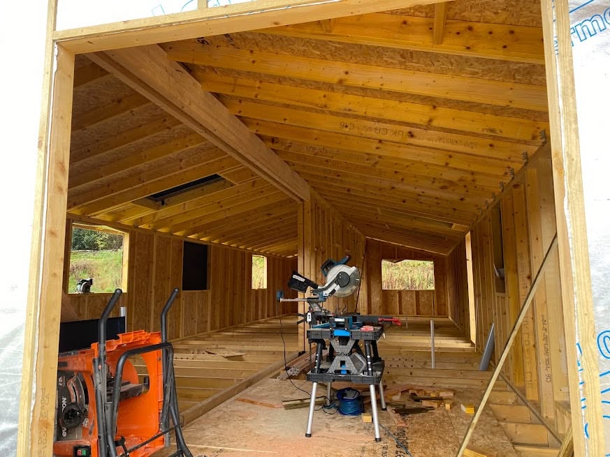Timber-frame building interior under construction with exposed roof joists