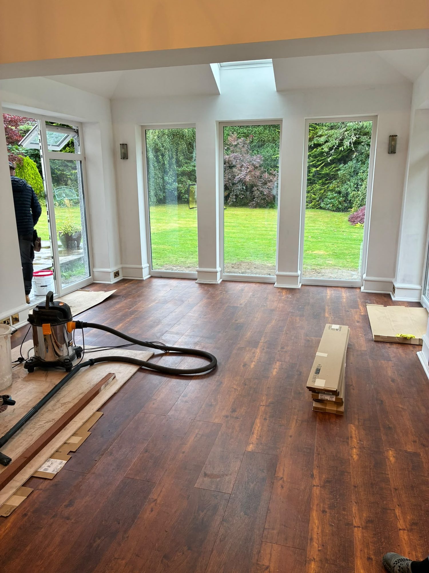 House extension interior with glazed doors during hardwood floor fitting