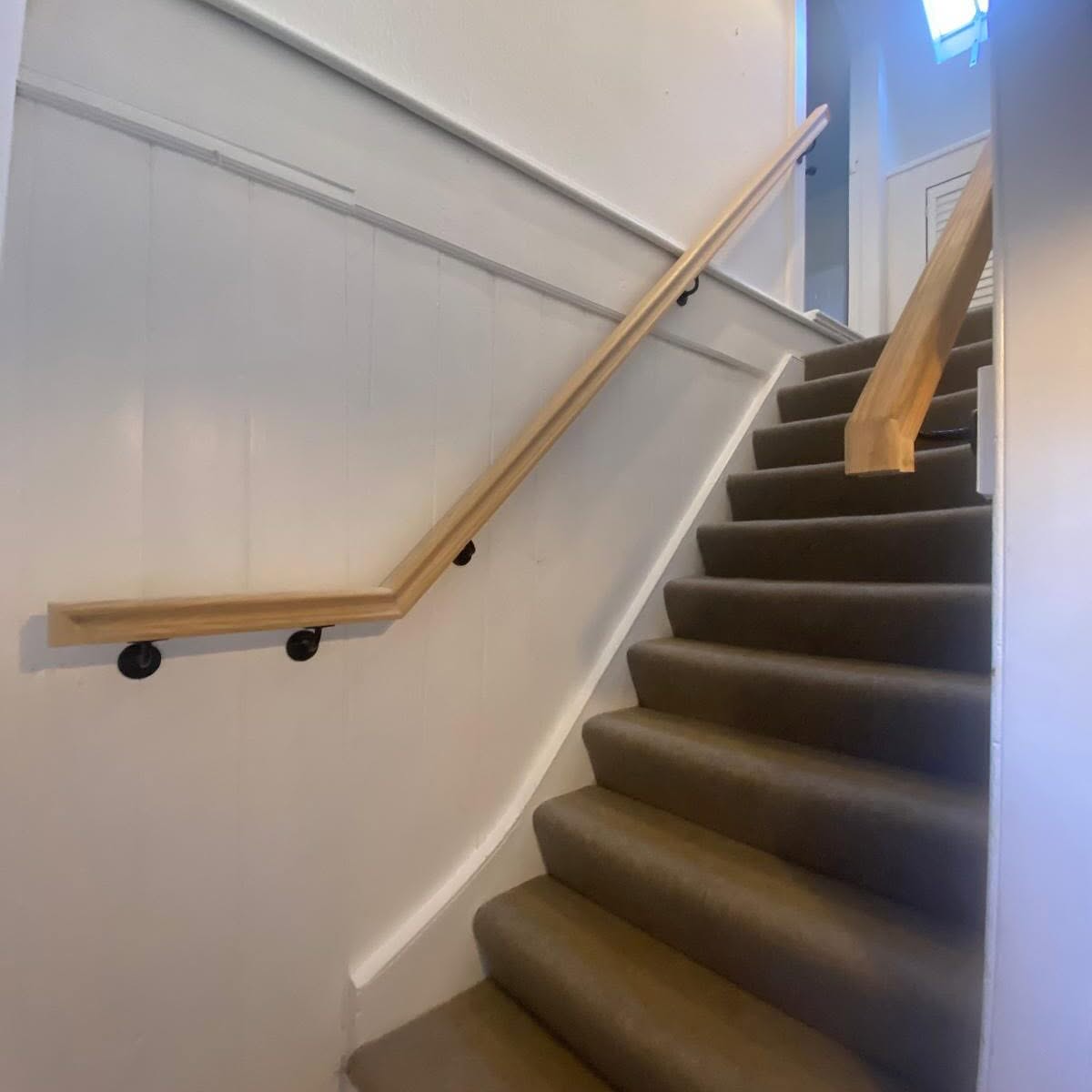 Finished carpeted staircase with timber handrail