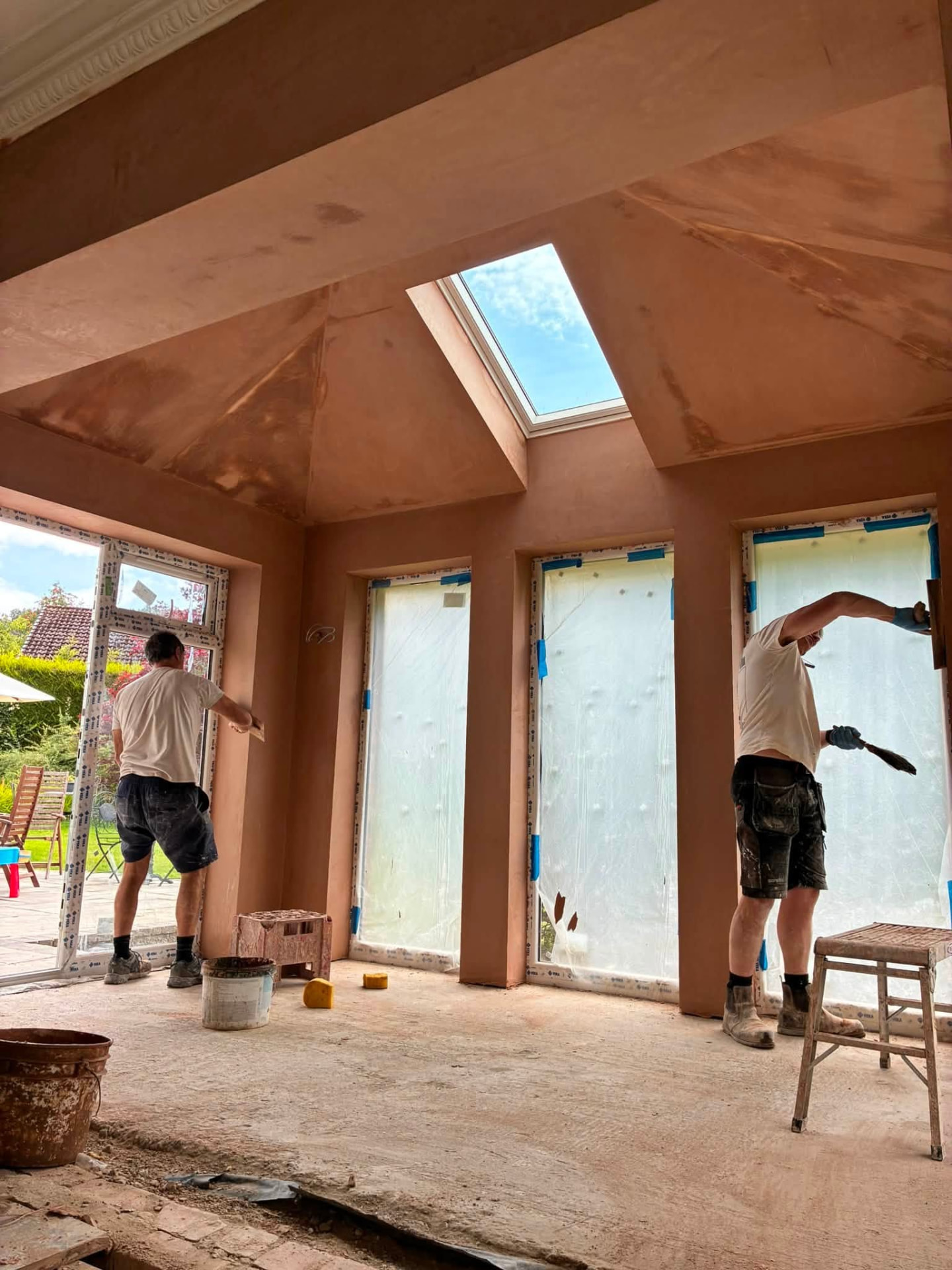 Tradespeople plastering a vaulted extension interior with a rooflight