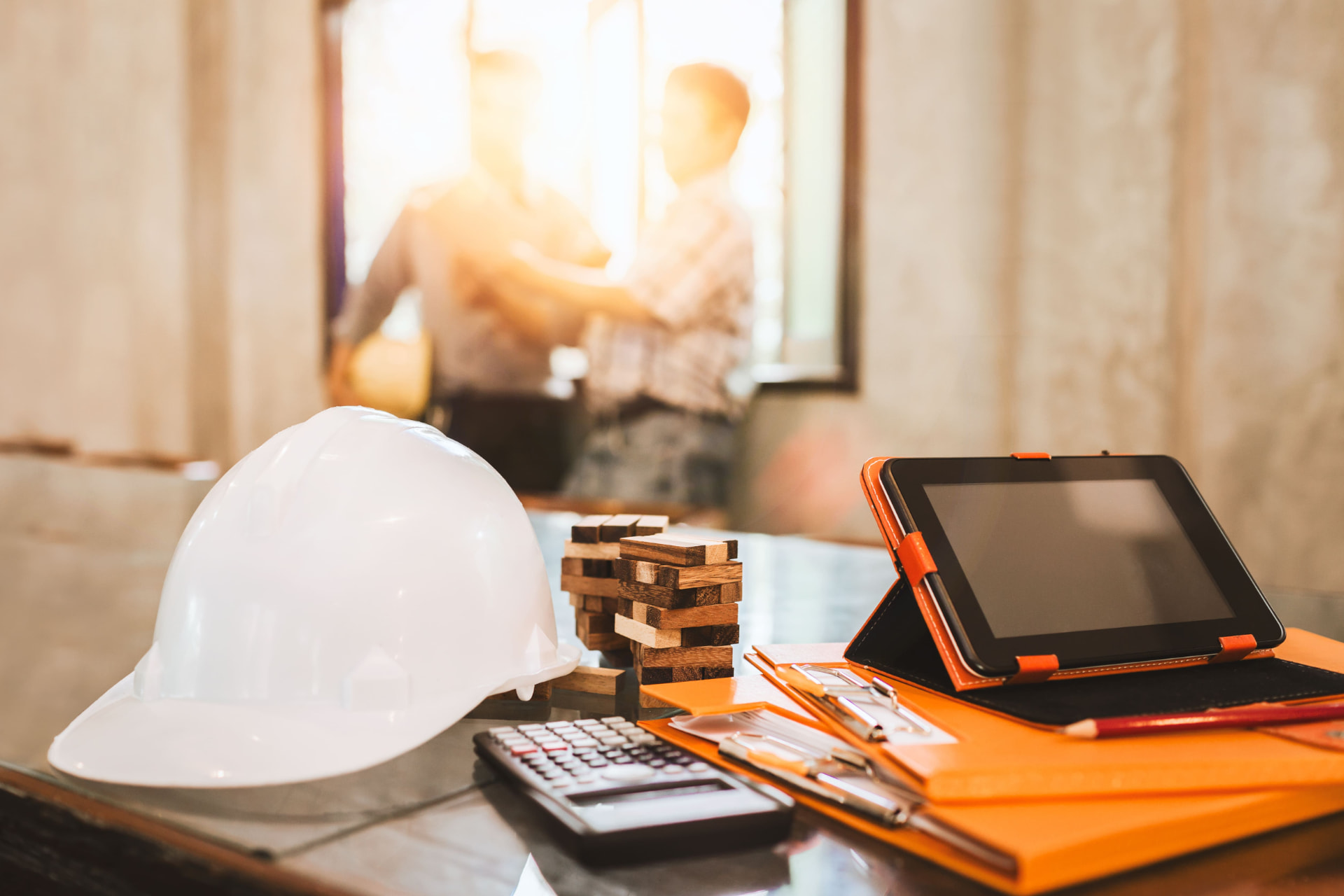 Hard hat, tablet, calculator and folders on a project planning desk