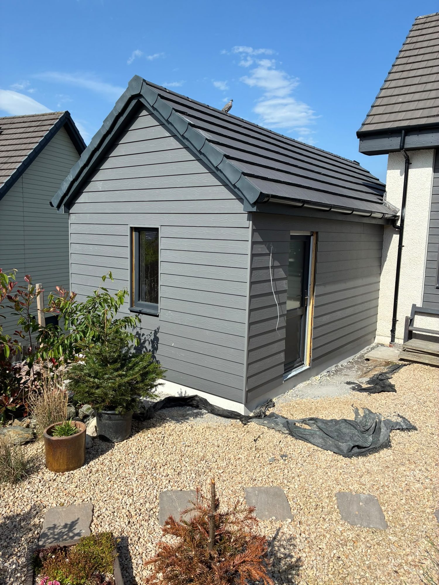 New-build detached garage with grey timber cladding and slate roof