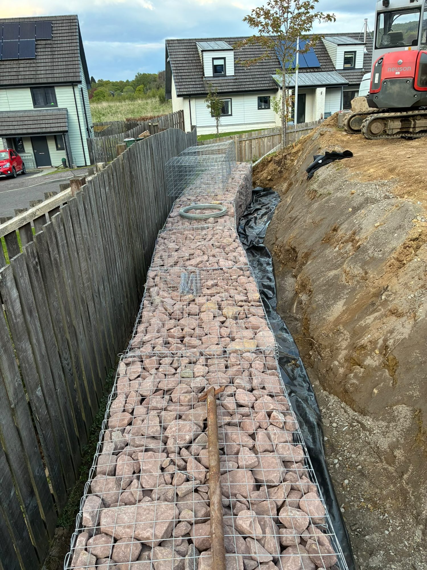 Gabion retaining wall groundworks along a garden boundary