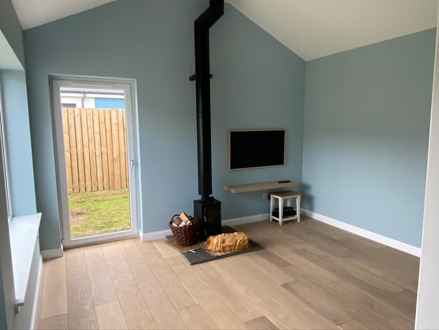 Finished room with blue walls, timber flooring and a wood-burning stove