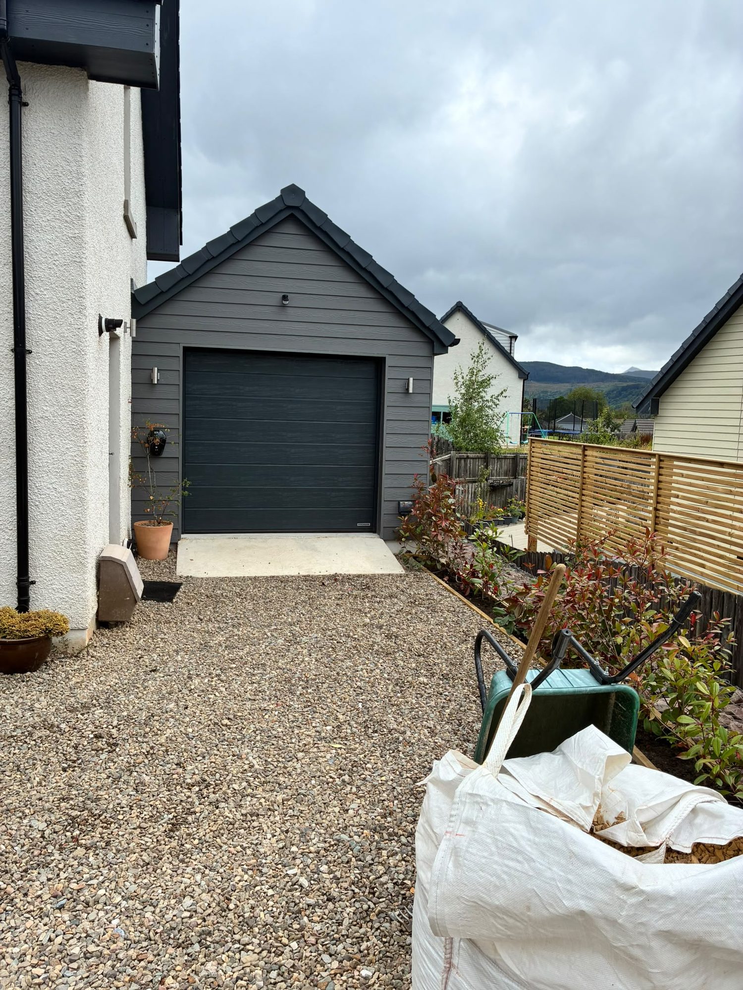 Completed new-build detached garage with roller door and gravel driveway