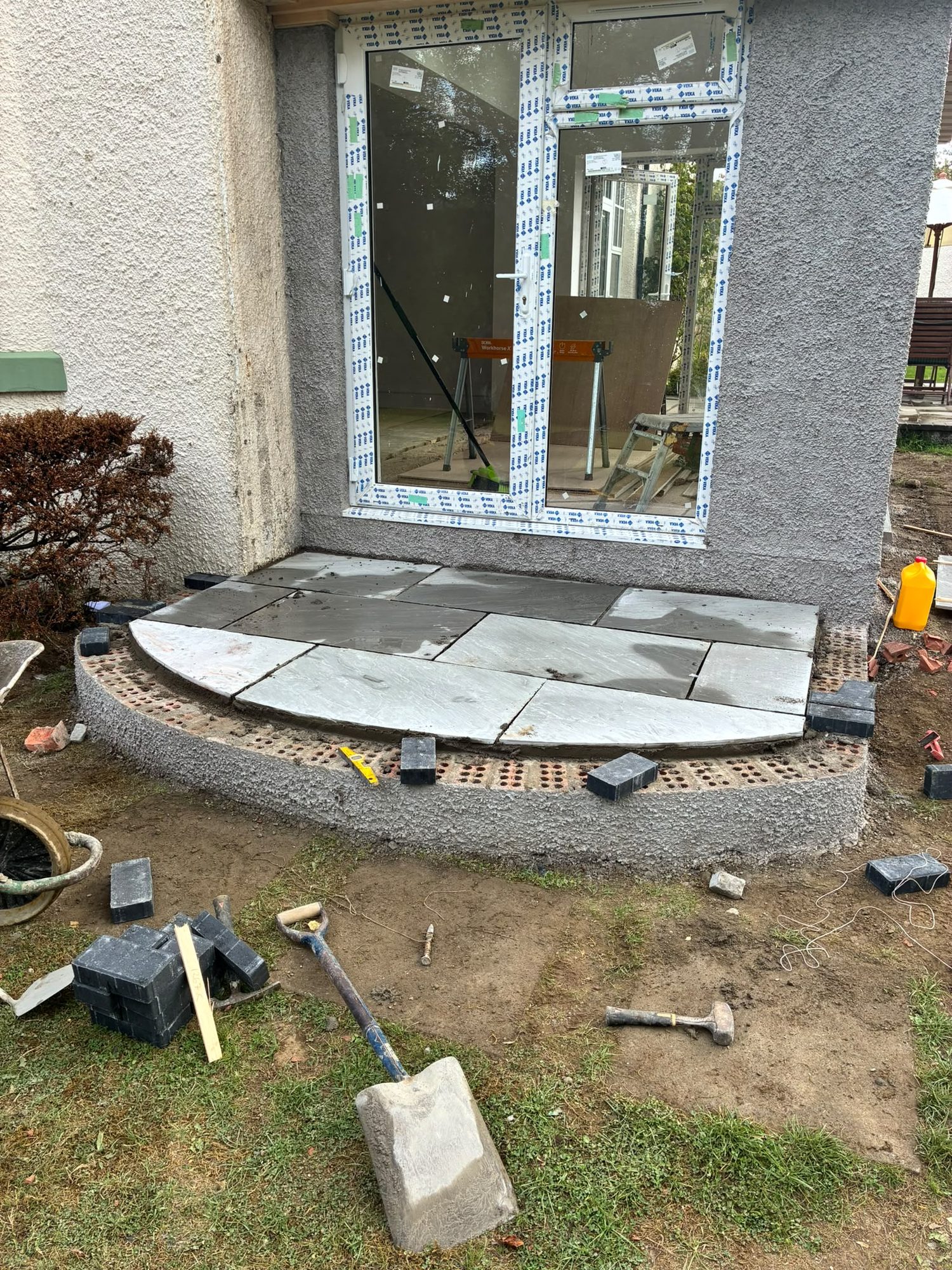 Curved entrance step and blockwork being built outside glazed doors
