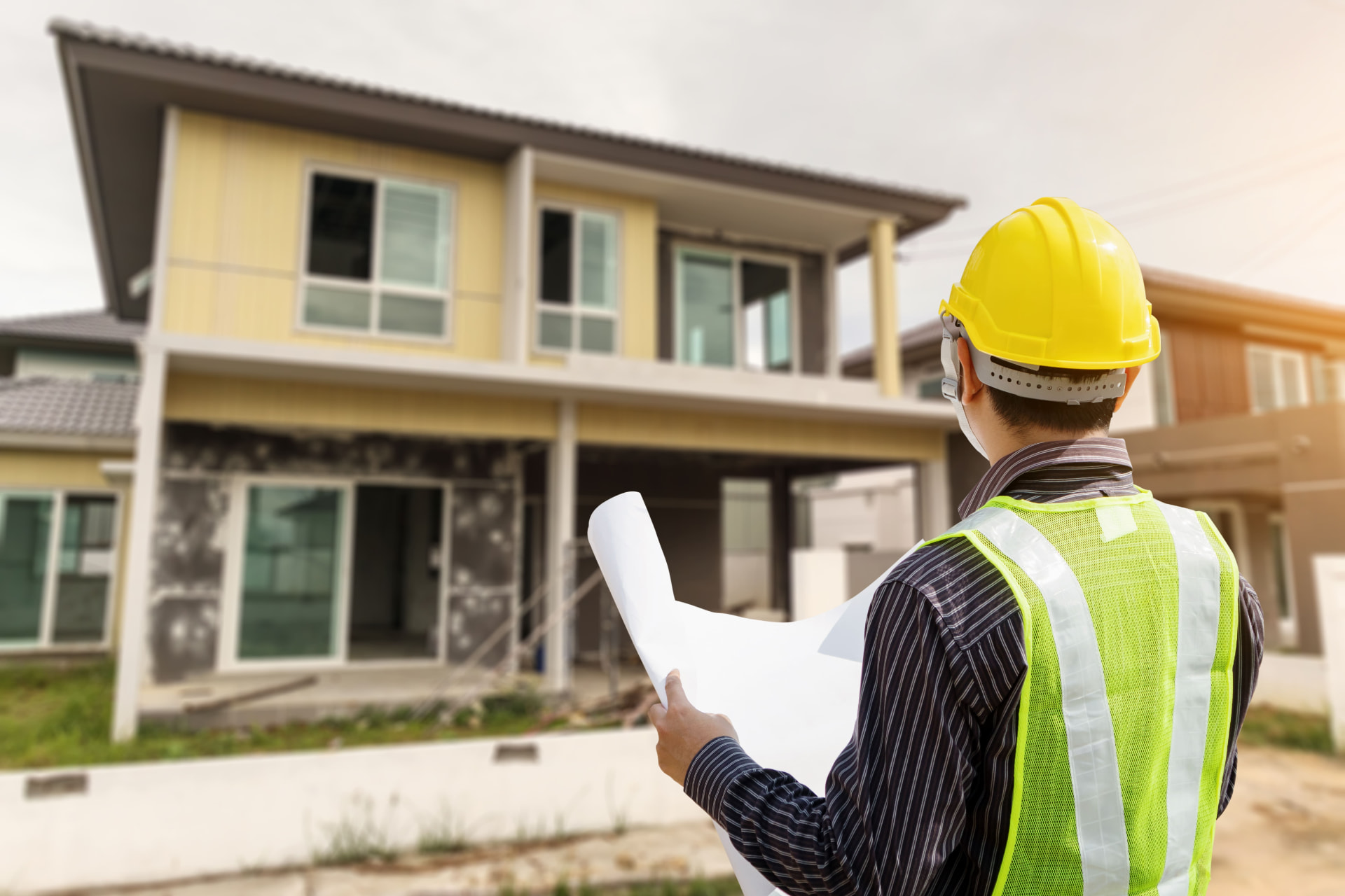 Builder holding plans outside a house under construction