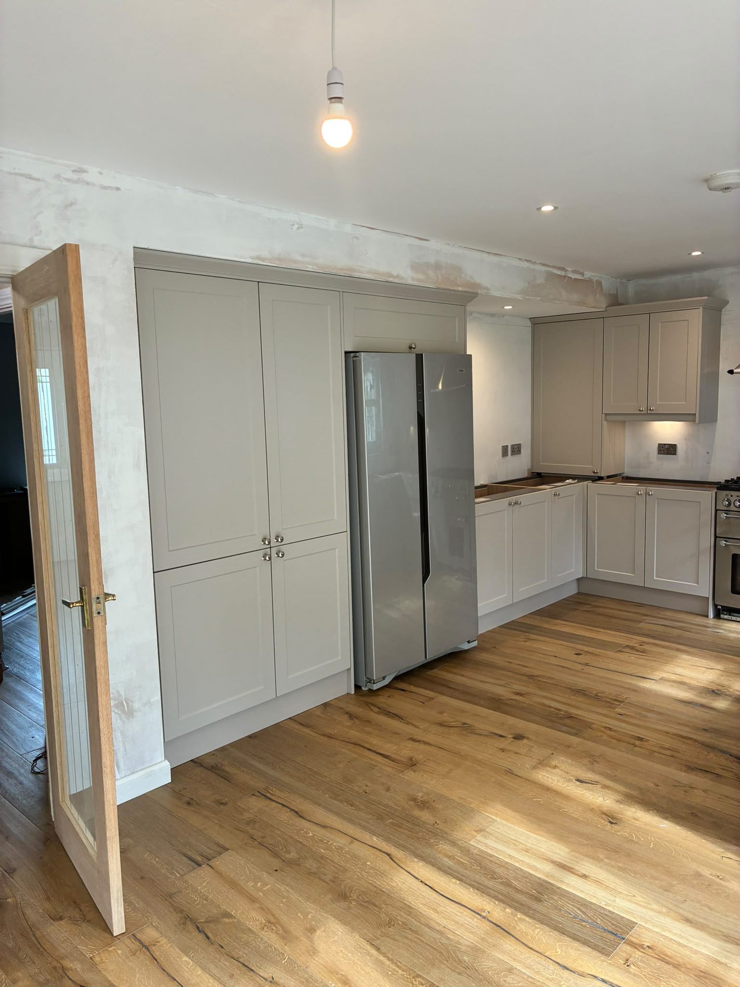 Renovated kitchen with tall larder units and oak floor